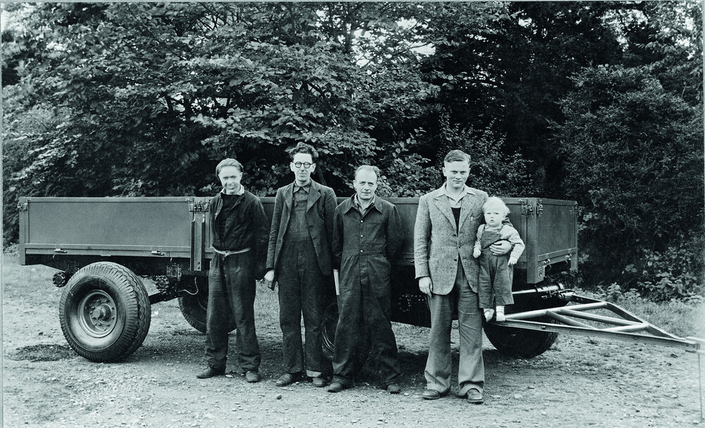1947 - Anthony Bamford in his father's arm. From left are employees Bill Hirst, Arthur Harrison and Bert Holmes.jpg